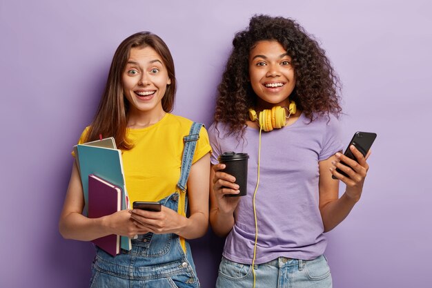 Studio shot of girlfriends posing with their phones