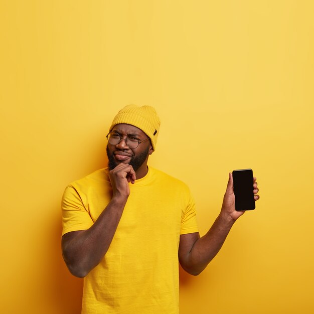 Studio shot of handsome guy with glasses posing with his phone