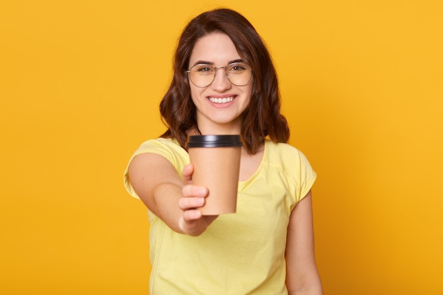 Studio shot of happy Caucasian woman holds take away cup of coffee or tea