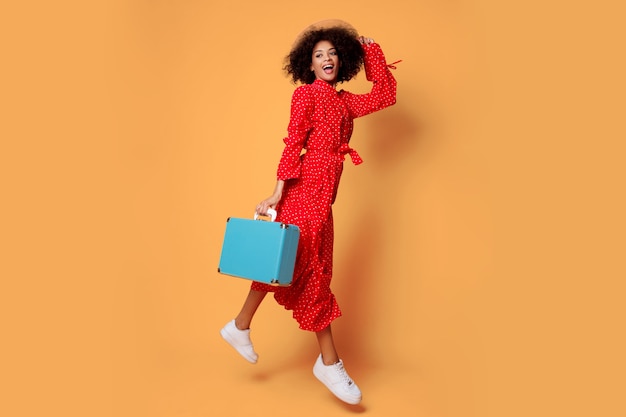 Studio shot of happy playful black woman fooling around and jumping on orange