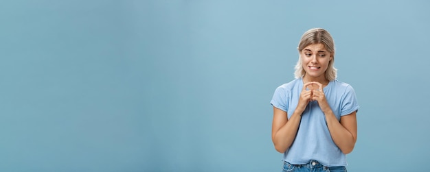 Free photo studio shot of insecure and timid silly girlfriend with blond hair clenching teeth looking shy down