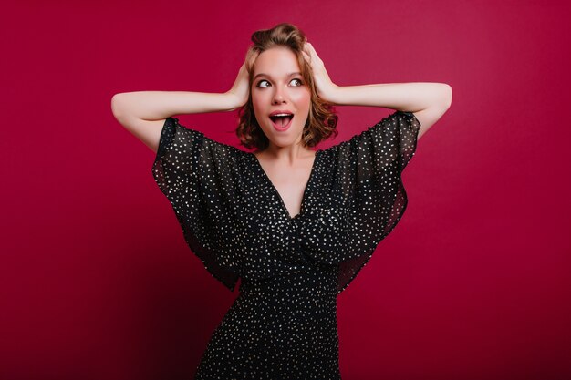 Studio shot of joyful white lady expressing surprised emotions