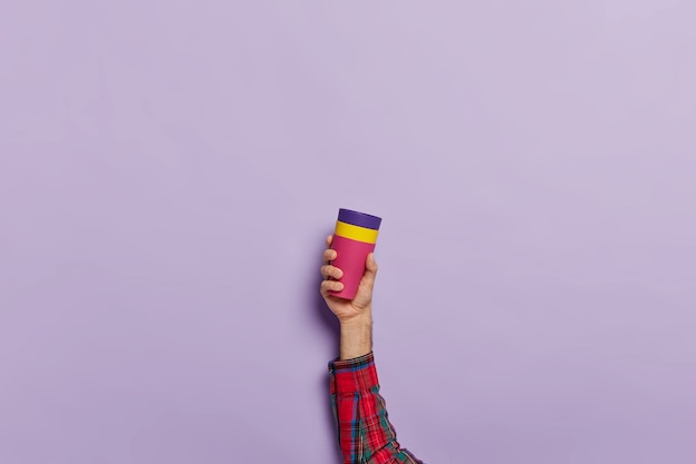 Studio shot of male hand holds coffee mug with hot beverage