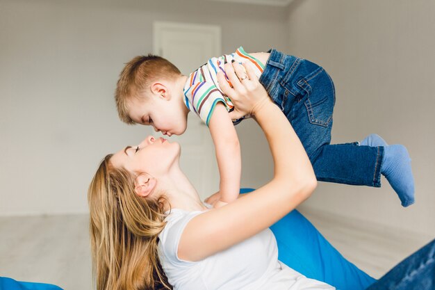 彼女の子供と遊ぶ母のスタジオ撮影。ママは彼女の腕の中で少年を保持しています。