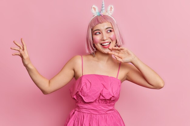 幅広い笑顔で満足しているアジアの女性は 髪型をおかしく さりげなく服を着て カフェのテーブルに座って レクリエーションの時間を楽しんでいます レストランで一人で休む美しい日本人女性 無料の写真