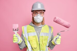 Студийный снимок серьезного мужчины-строителя, использующего инструменты для ремонта дома
