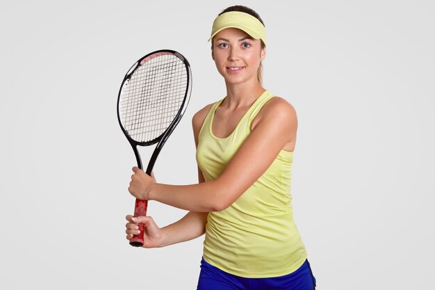 Studio shot of pleasant looking sporty determined female wears court cap