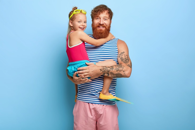 Free Photo studio shot of pleased ginger father and daughter posing in pool outfits