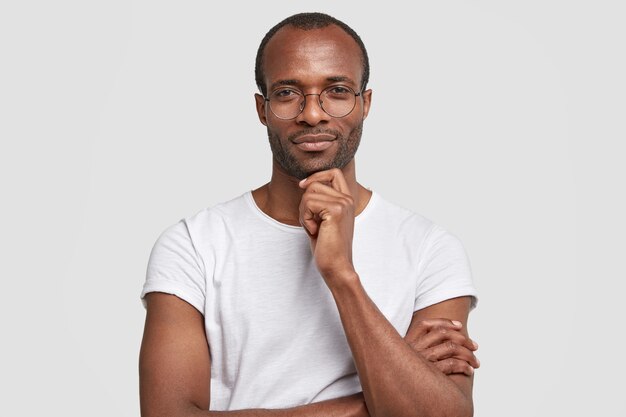 Studio shot of serious black man keeps hand under chin