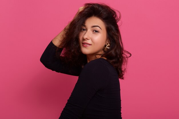 Studio shot of smiling girl with dark hair and pleasant appearance