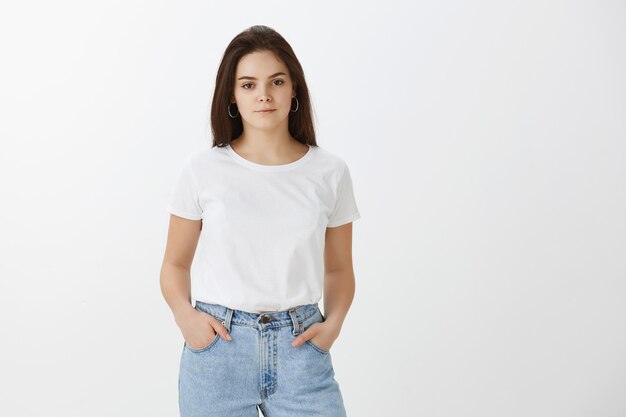 Studio shot of stylish confident young woman posing against white wall