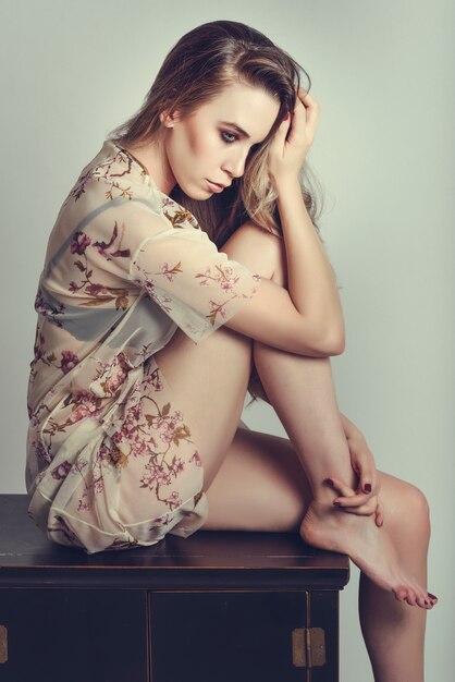 Studio shot. Thoughtful woman with long hair and blue eyes wearing beautiful shirt.