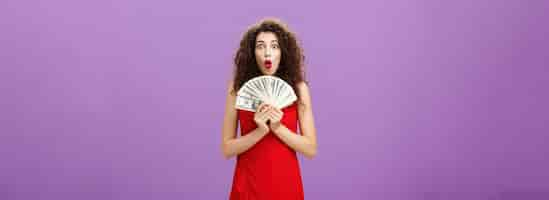 Free photo studio shot of woman being lucky in casino winning lots of cash holding money in hands saying wow wi