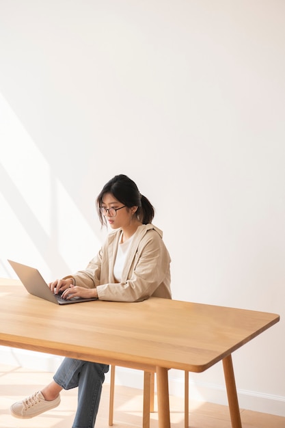 Free photo studious asian woman working at home using a laptop