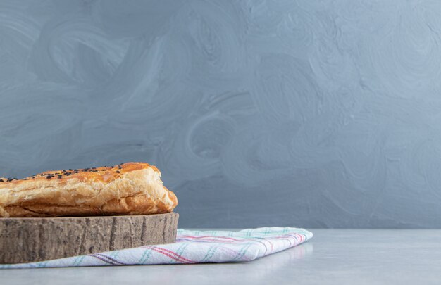 Stuffed pastry with sesame seeds on wood piece. 