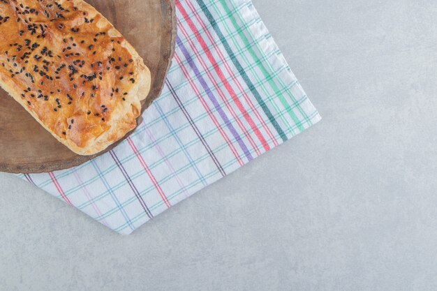 Stuffed pastry with sesame seeds on wood piece. 