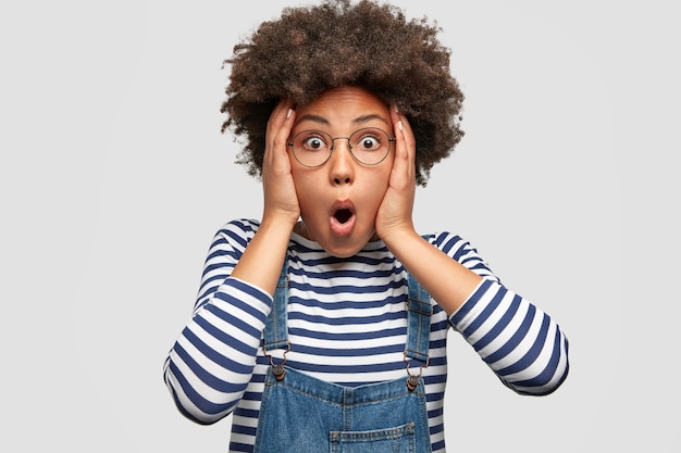 Stunned African American female stares at camera and keeps mouth opened