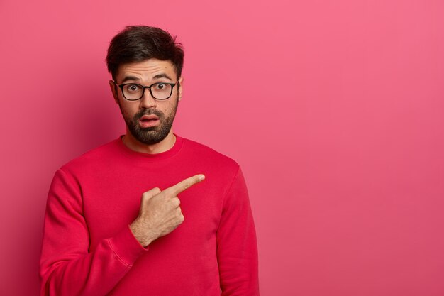 Stunned bearded young man shows unbelievable presentation