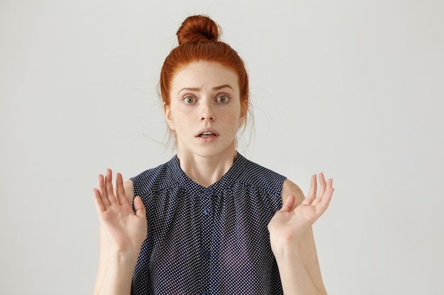 stunned or frightened young lady with ginger hair gesturing with both hands, having shocked and scared expression, afraid and terrified with something scary. Body language