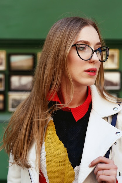 Free photo stunning blonde in glasses poses in white jacket on the street