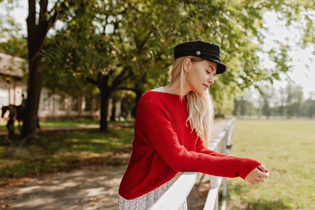 Stunning blonde with elegant style feeling good outside. Charming girl posing near old building in the park.