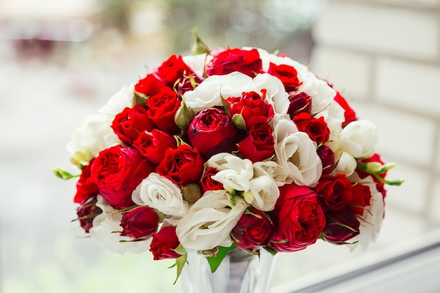 Stunning bouquet made of dark red and white roses stands in glas