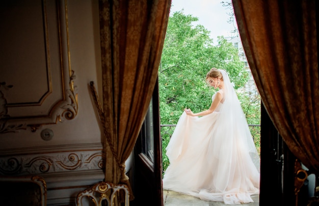 ウェディングドレスの素晴らしい花嫁は、高級ホテルの部屋のバルコニーにポーズ