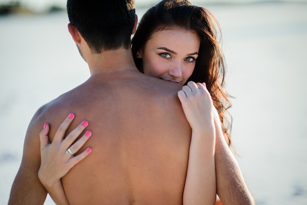 Stunning brunette hugs naked man and holds her hands on his back