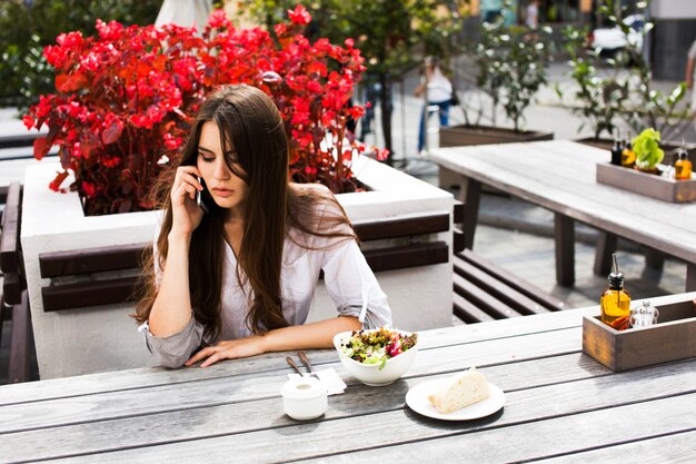 Stunning brunette with long hair sits before red flowers