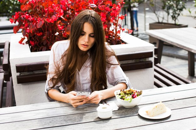 Stunning brunette with long hair sits before red flowers