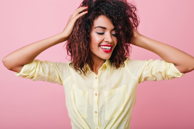 Stunning girl with dark-brown curls having fun during. pleased black woman wears elegant yellow shirt.