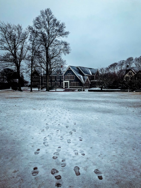 Free photo stunning view of footprints in the snowy street heading to a big house with big windows and trees