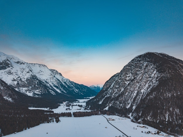 Stunning view of a mountain range in a cold and snowy day during sunset