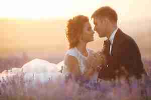 Free photo stunning wedding couple of bride and groom on sunset in lavender