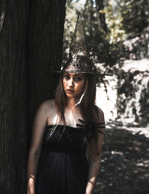 Free photo stunning witch with creepy spider in sunny forest