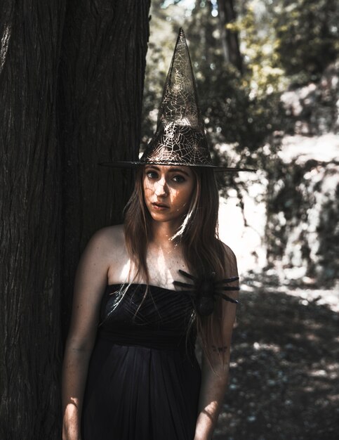 Stunning witch with creepy spider in sunny forest