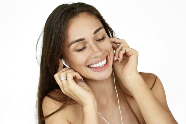 Stunning woman with earphones dances on white background