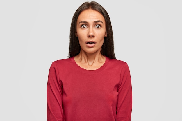 Stupefied brunette young woman stares with bugged eyes, opens mouth