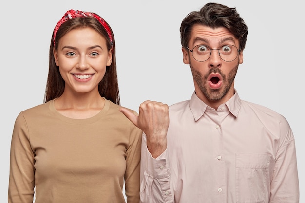 Free photo stupefied young couple posing against the white wall