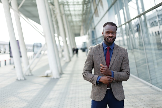 Stylish African American black businessman poses in a suit before a modern building