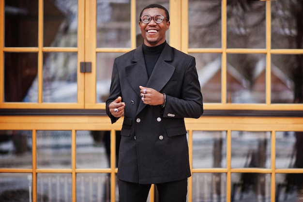 Стильный афро-американский джентльмен в элегантной черной куртке Богатый модный афро-мужчина у окна