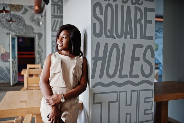 Stylish african american girl posed at modern cafe with mobile phone at hands