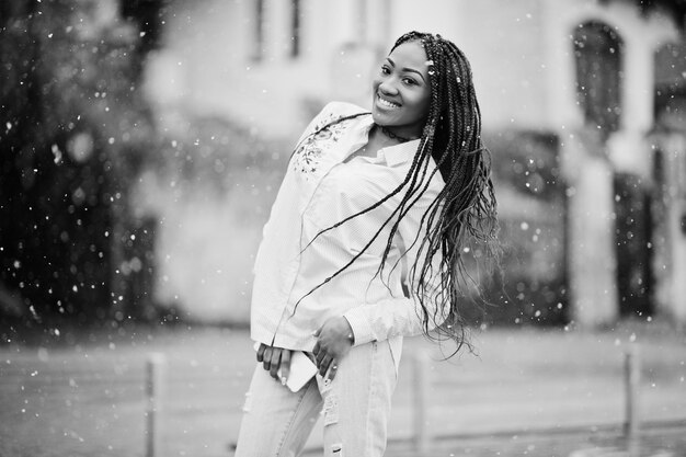 Stylish african american girl with dreads holding mobile phone at hand outdoor snowy weather