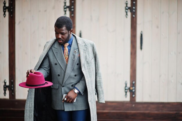 Stylish African American man model in gray coat jacket tie and red hat