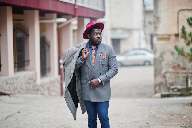 Stylish African American man model in gray coat jacket tie and red hat