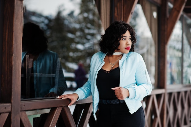 Stylish african american plus size model against wooden cafe at winter day