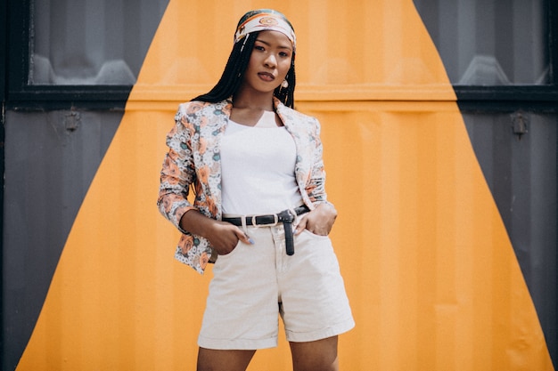 Stylish african american woman by the colored wall