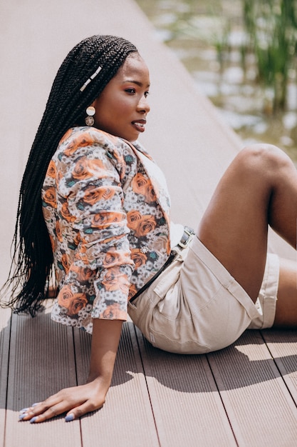 Stylish african american woman sitting by the lake in the park