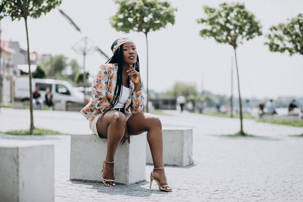 Stylish african american woman sitting on a rock in the park