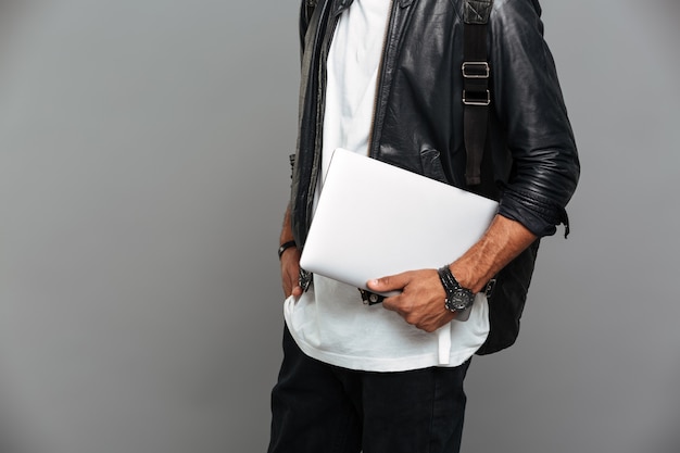 стильный африканский человек в кожаной куртке держит ноутбук